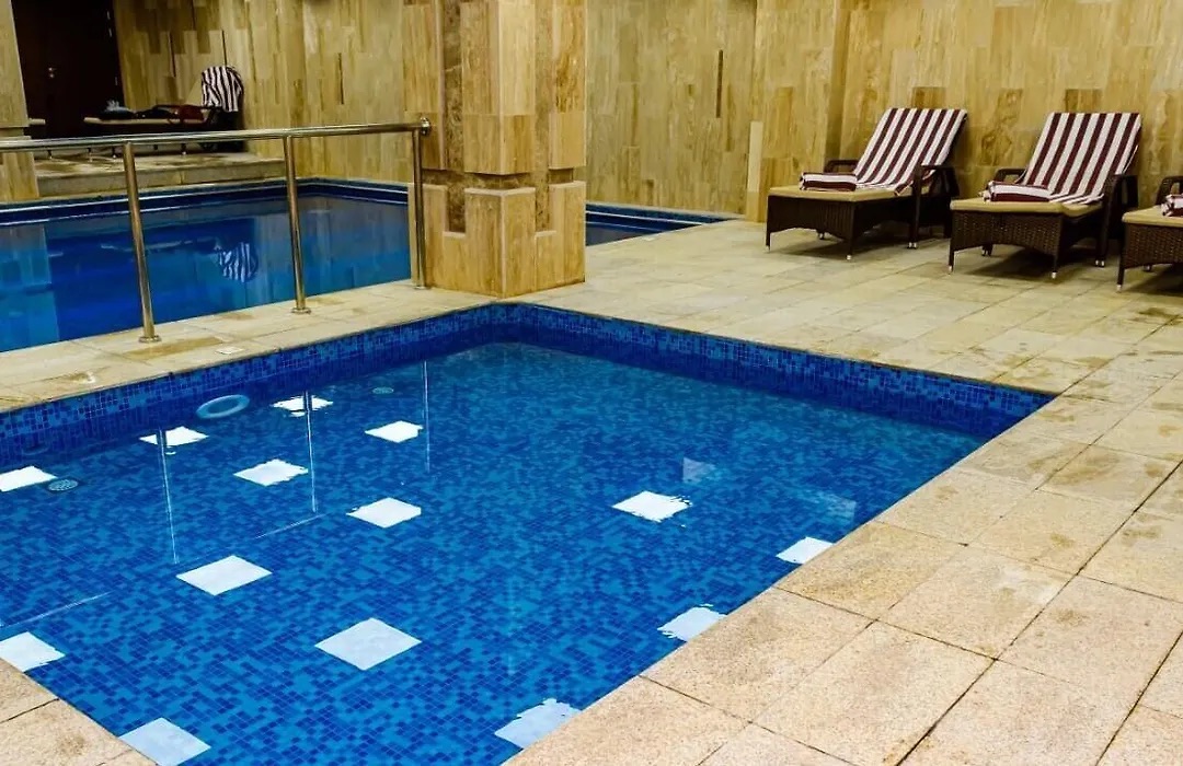 Heated indoor pool with white tiles and wooden loungers