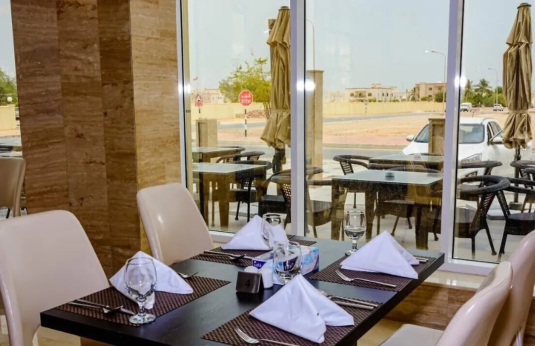 Restaurant tables set with white napkins beside a window onto the street