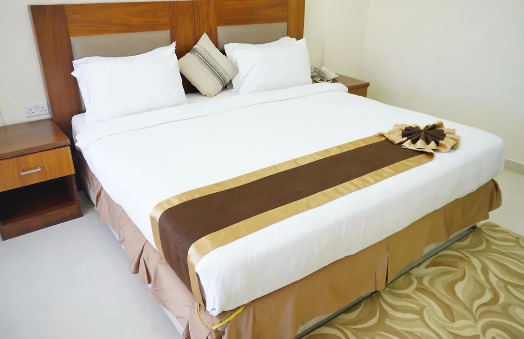 Deluxe Room with a king bed, white linen and a brown bed runner
