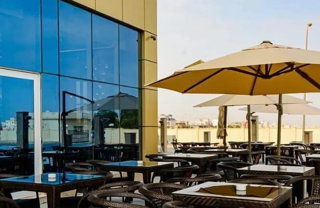 Terrace tables under a parasol by the glass façade